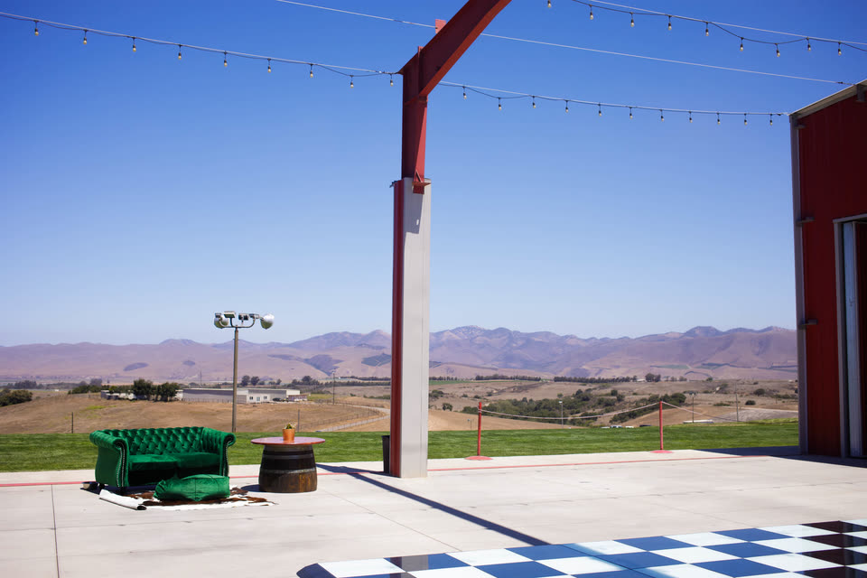 A green velvet sofa and wine-barrel table on the terrace, looking out over the valley to the mountains.